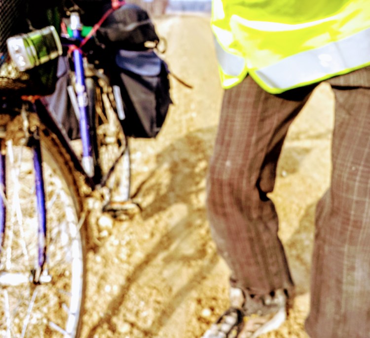 Part of a blue touring bicycle and legs of the cycler