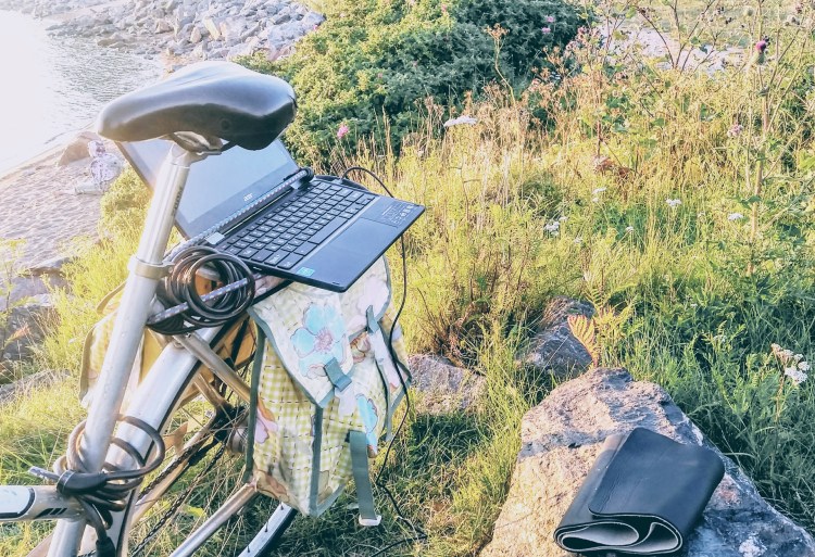 A laptop on the back rack of a bicycle, used as desk