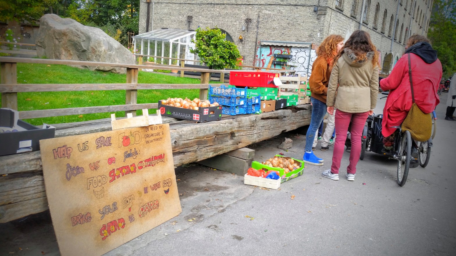 People standing in front of boxes full of vegetables.