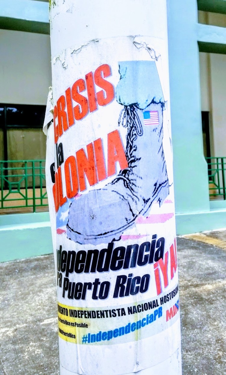 A poster on a light pole: a soldier shoe with the USA flag stepping on the PR flag
